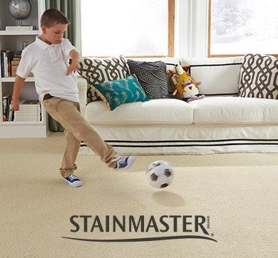 Young boy kicking a soccer ball in a living room with Stainmaster® carpet