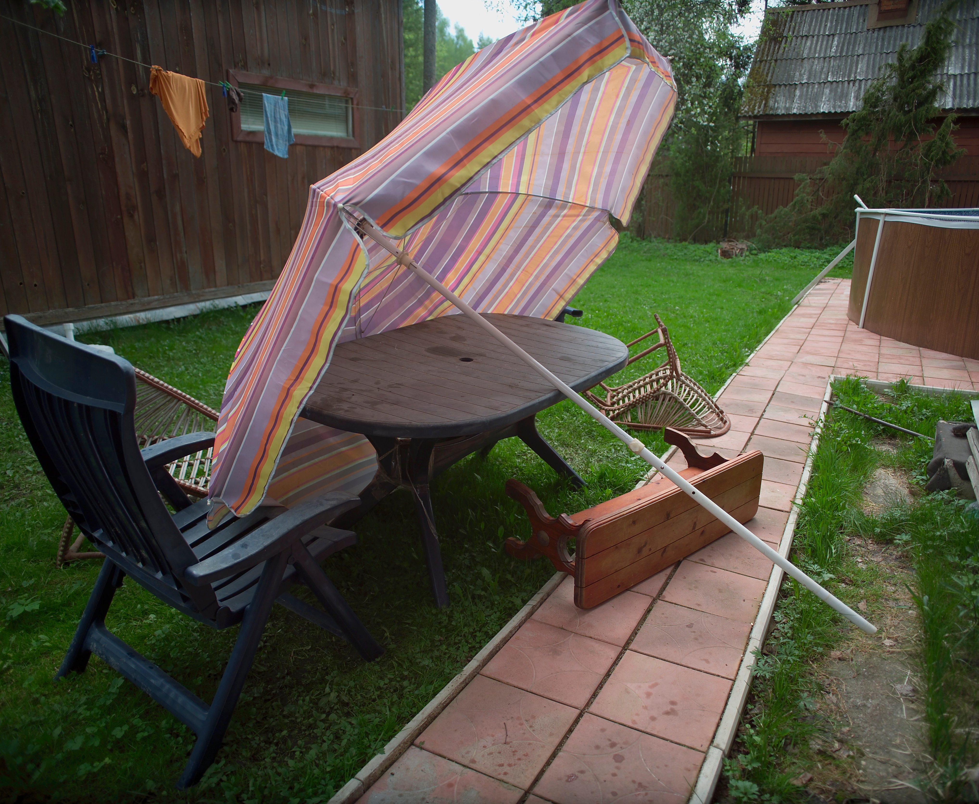 patio chairs, table, and umbrella blown over by wind